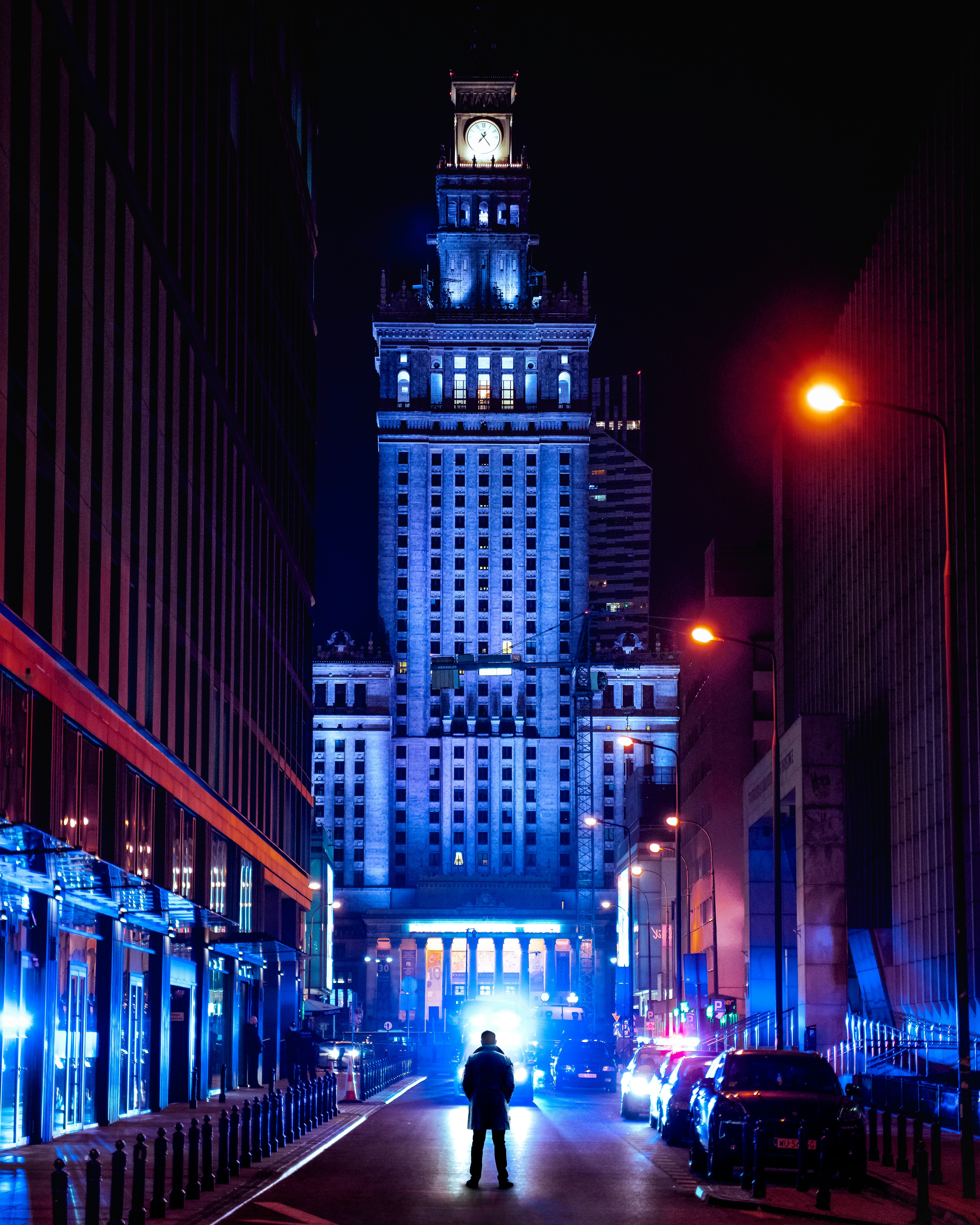 people walking on sidewalk near high rise buildings during night time